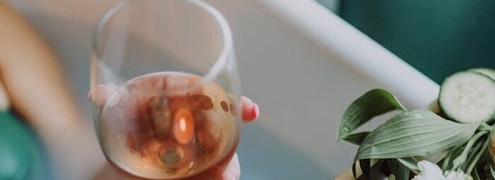 A serene bath setting with wine, candles, and flowers for a relaxing spa experience.