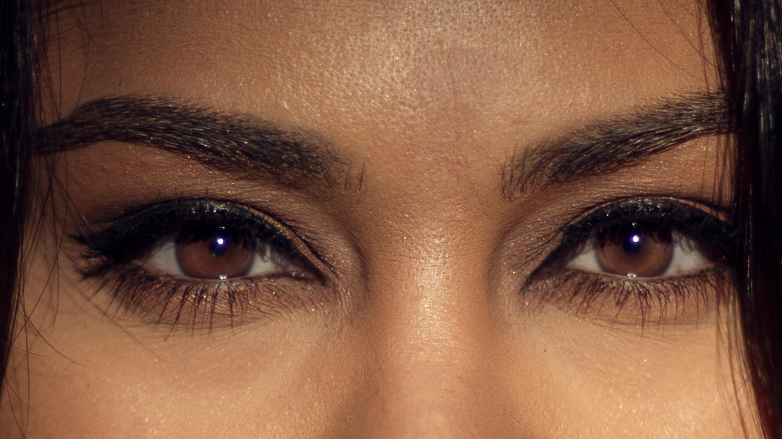 A detailed close-up of a woman's brown eyes highlighting makeup and natural beauty.
